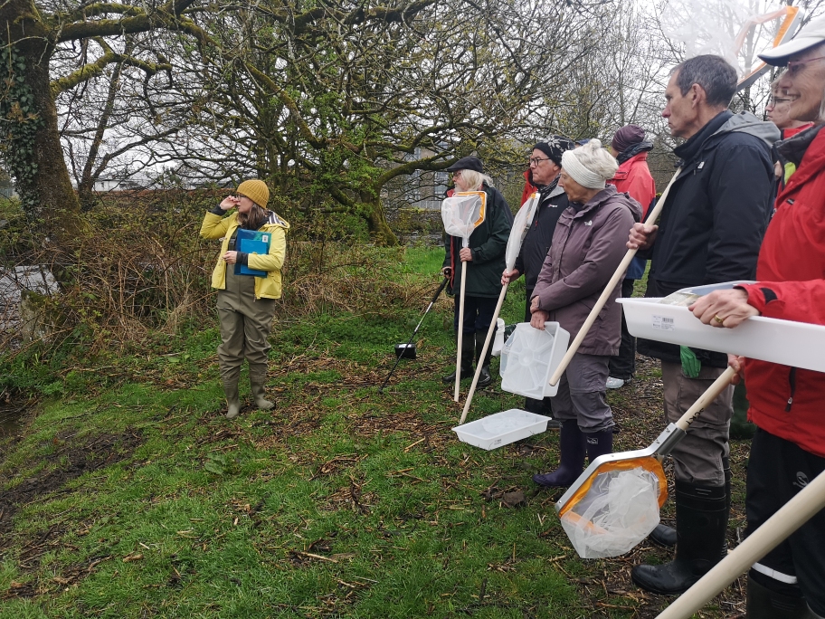 Volunteers with water sampling tools stand on the banks of the river Kent