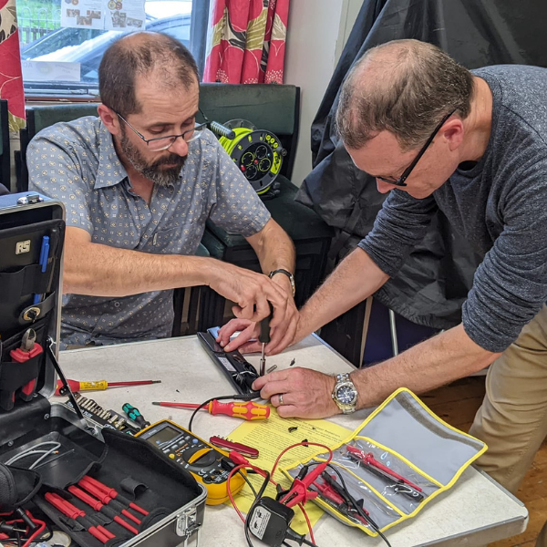 Two people using tools to repair an electrical item at a Repair Café in Staveley.
