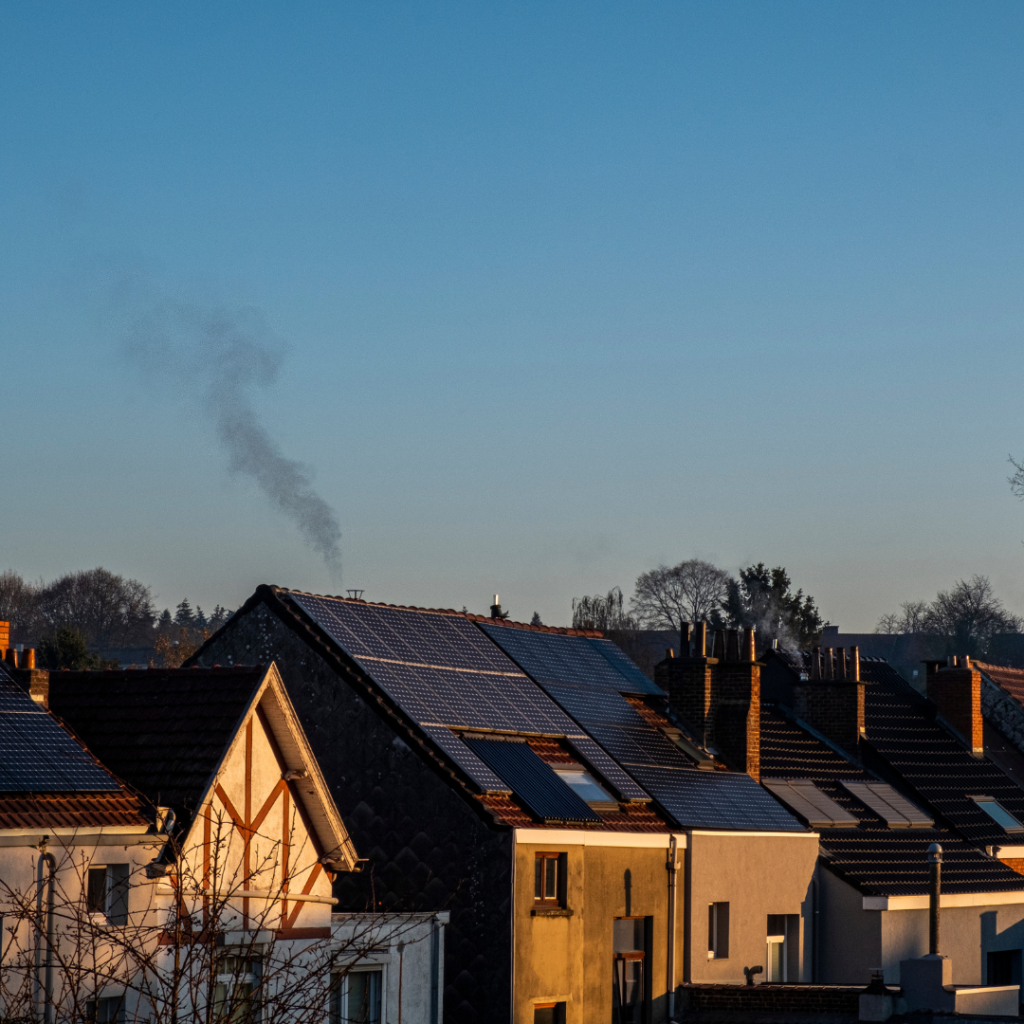 A row of houses under a blue sky – one has solar panels on the roof.