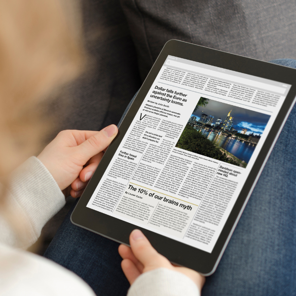 An over-the-shoulder shot of a person using a tablet to read the news.